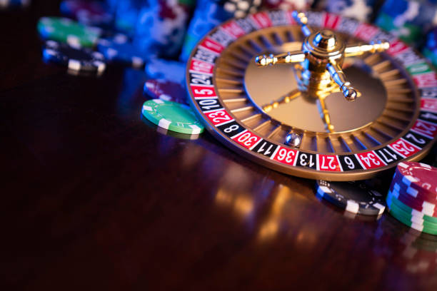 Ruleta, dados y fichas de póquer sobre fondo bokeh.